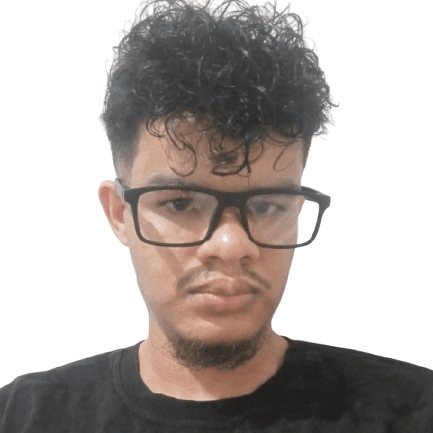 Young man with dark curly hair, wearing black-framed glasses, with a mustache and goatee. He is wearing a black t-shirt and has a neutral expression, looking at the camera. The background is a plain white wall.